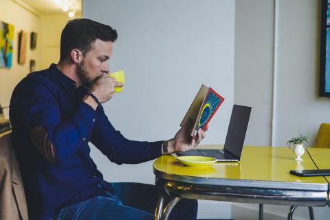 Homem olhando revista e tomando café