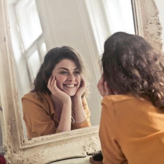 mujer feliz mirando en el espejo